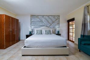 A bedroom with a large bed, wooden wardrobe, and a view of the outside.