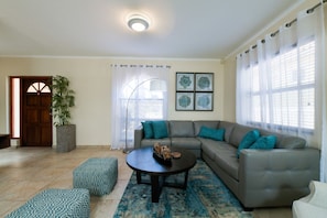 A living room with a sectional sofa, a round coffee table, and a potted plant. - Villa Retreat: 3BR w Private Pool near Palm Beach (Noord)
