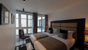 Quarto de hotel moderno com uma cama grande, uma escrivaninha e vista para a cidade.