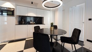 Uma cozinha moderna com bancada preta, armários brancos e uma mesa de jantar redonda com cadeiras pretas.