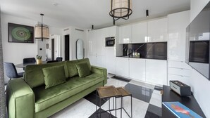 A modern living room with a green sofa, a coffee table, and a kitchen area with white cabinets and a black countertop. - Quartier d'Hiver, 4 stars, Beautiful apartment close to the Champs-Elysées (París)