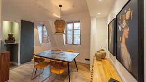 A modern dining area with a wooden table, yellow chairs, and a hanging light fixture. - Comte de Clare, 4 stars, Cosy apartment close to the Champs-Elysées (París)