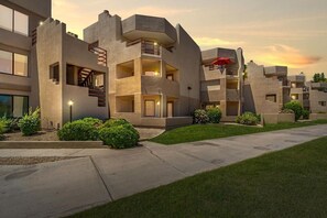 A modern multi-story building with balconies, a central staircase, and a well-maintained lawn. - Nicely appointed condo on the golf course and running/biking path! (Scottsdale)