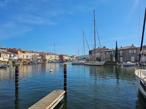 A marina with boats docked, a wooden pier, and colorful buildings along the waterfront. - Close to the beach and shops, House 8 people  et  mooring 12 m (PORT GRIMAUD)