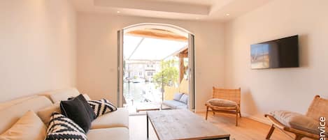 Un salon moderne avec un canapé, une table basse et deux fauteuils en osier.