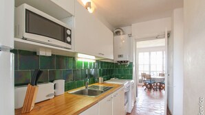 A kitchen with white cabinets, a microwave, a toaster, and a sink. - On the beach 2 bedrooms flat 4/6 persons (PORT GRIMAUD)