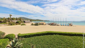 A beach with a clear sky, a sandy area, and a few buildings in the background. - On the beach 2 bedrooms flat 4/6 persons (PORT GRIMAUD)