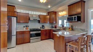 A modern kitchen with wooden cabinets, stainless steel appliances, and a granite countertop. - Paradise Ocean View, 2Br/2Ba (Keaau)