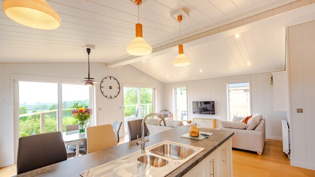 Una cocina amplia con una isla grande, elegantes lámparas colgantes y vistas al exterior.