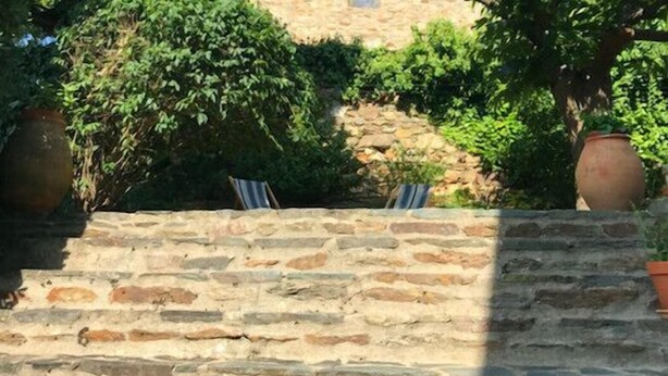 A stone building with a small arched window, surrounded by lush greenery and a stone wall. - Charming House In Garde Freinet With Garden (La Garde-Freinet)