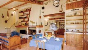 A dining area with a table set for four, wooden furniture, and shelves with kitchenware. - Charming House In Garde Freinet With Garden (La Garde-Freinet)