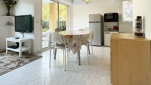 A modern kitchen with a dining area, a TV, and a refrigerator.
