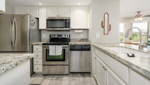 A modern kitchen with stainless steel appliances, white cabinetry, and a marble countertop. - Villa Stone Creek 2 Bedroom Condo by RedAwning (Scottsdale)