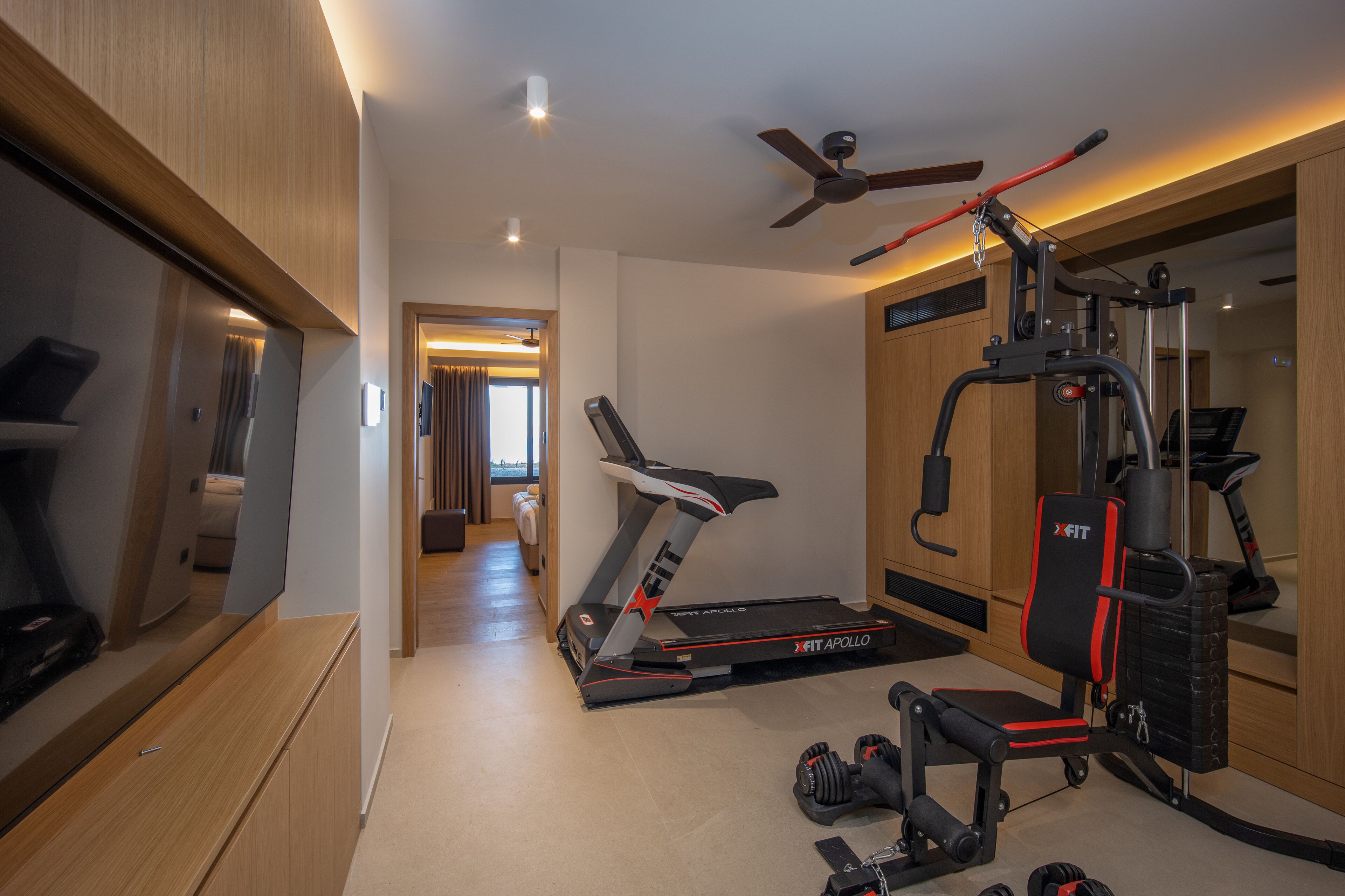 Et moderne fitnessrum med løbebånd, vægtbænk og forskellig træningsudstyr.