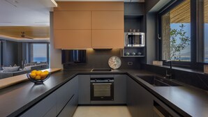 A modern kitchen with a central island, built-in oven, and a large window offering a view. - Villa Nereid 5 bedroom villa with infinity heated pool (Rodia)
