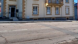 Ein mehrgeschossiges Gebäude mit einer symmetrischen Fassade, zahlreichen Fenstern und einem zentralen Balkon.