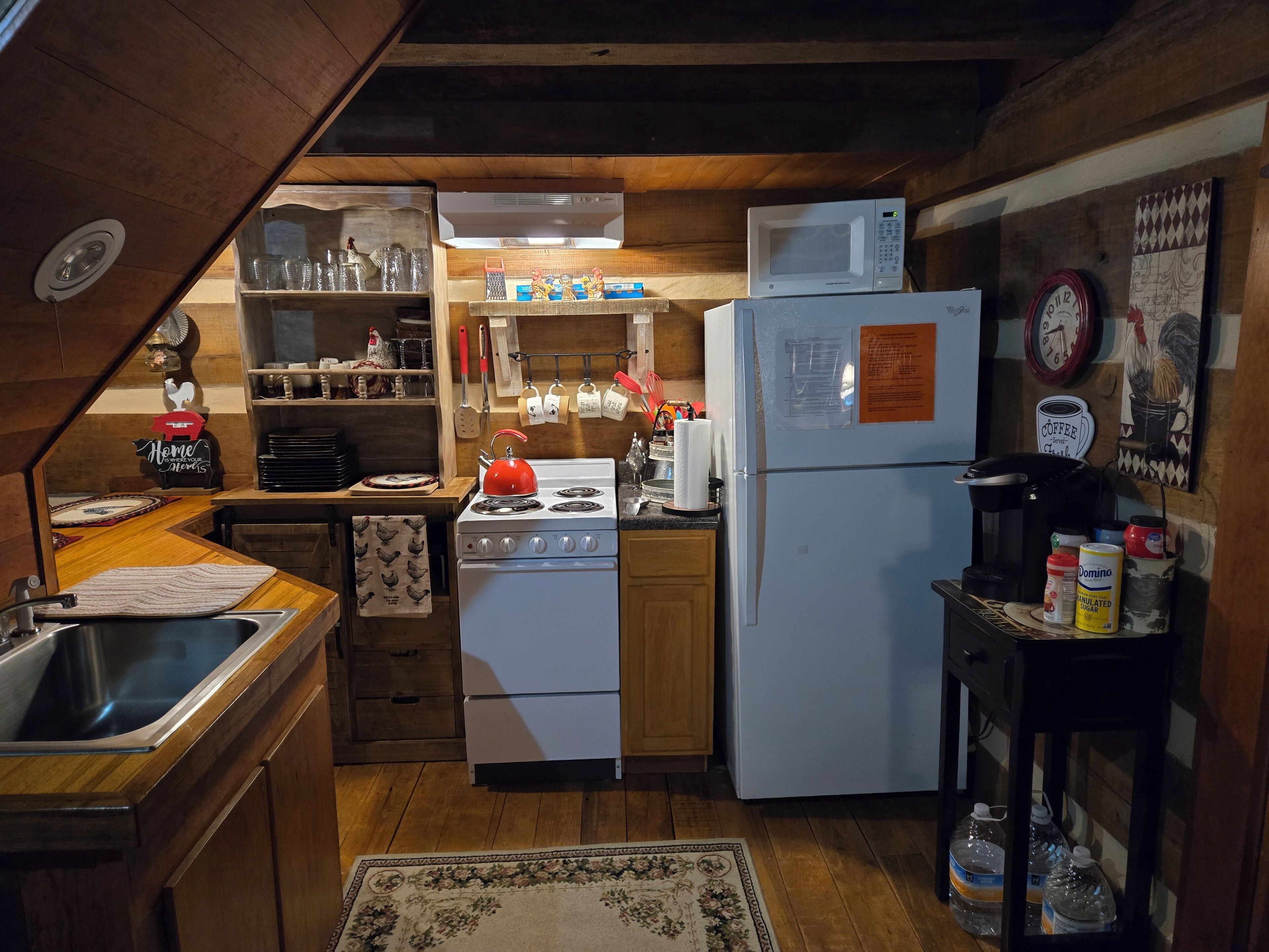 A compact kitchen with wooden cabinets, a stove, a microwave, and a refrigerator.