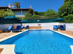 A swimming pool with blue water, surrounded by lounge chairs and umbrellas. - Villa Loretta - Private heated pool, two minutes' walk to tennis club (Carvoeiro)