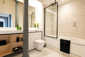 A modern bathroom with a toilet, sink, and bathtub.
