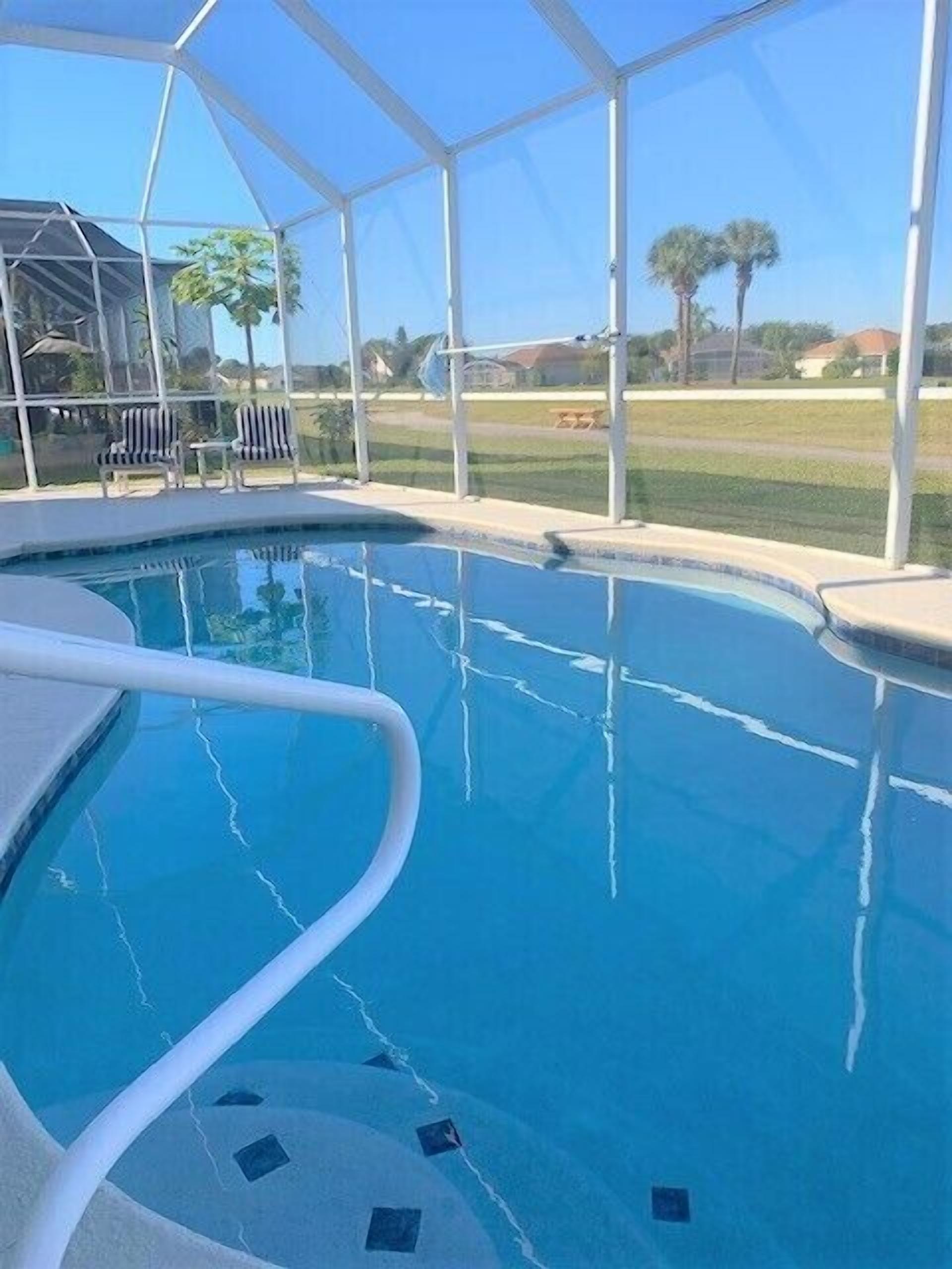 An indoor swimming pool with clear blue water, surrounded by a white fence.