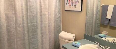 Un baño con inodoro, lavabo, espejo y un cuadro en la pared.