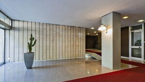 A modern lobby with a red carpet, a cactus in a planter, and a staircase leading to another area. - Studio Piccolo a Carignano by Wonderful Italy (Genoa)