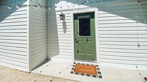 Una casa con puerta verde, felpudo y luces colgantes.
