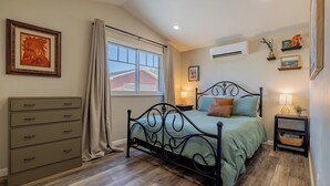 Un dormitorio con cama, cómoda y ventana con cortinas.