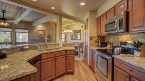 A spacious kitchen with granite countertops, wooden cabinets, a large island, and modern appliances. - 2BR Condo | Walk to Gondola | Pool, Hot Tubs and Fireplace! (Steamboat Springs)