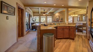A spacious kitchen with a large island, wooden cabinets, and a stone accent wall. - 2BR Condo | Walk to Gondola | Pool, Hot Tubs and Fireplace! (Steamboat Springs)