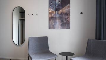Una habitación moderna con dos sillas grises, una pequeña mesa redonda y un cuadro abstracto grande en la pared.
