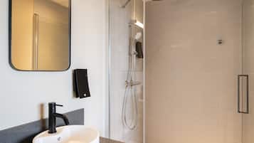 Une salle de bain moderne avec un lavabo blanc, un robinet noir et une douchette à main.