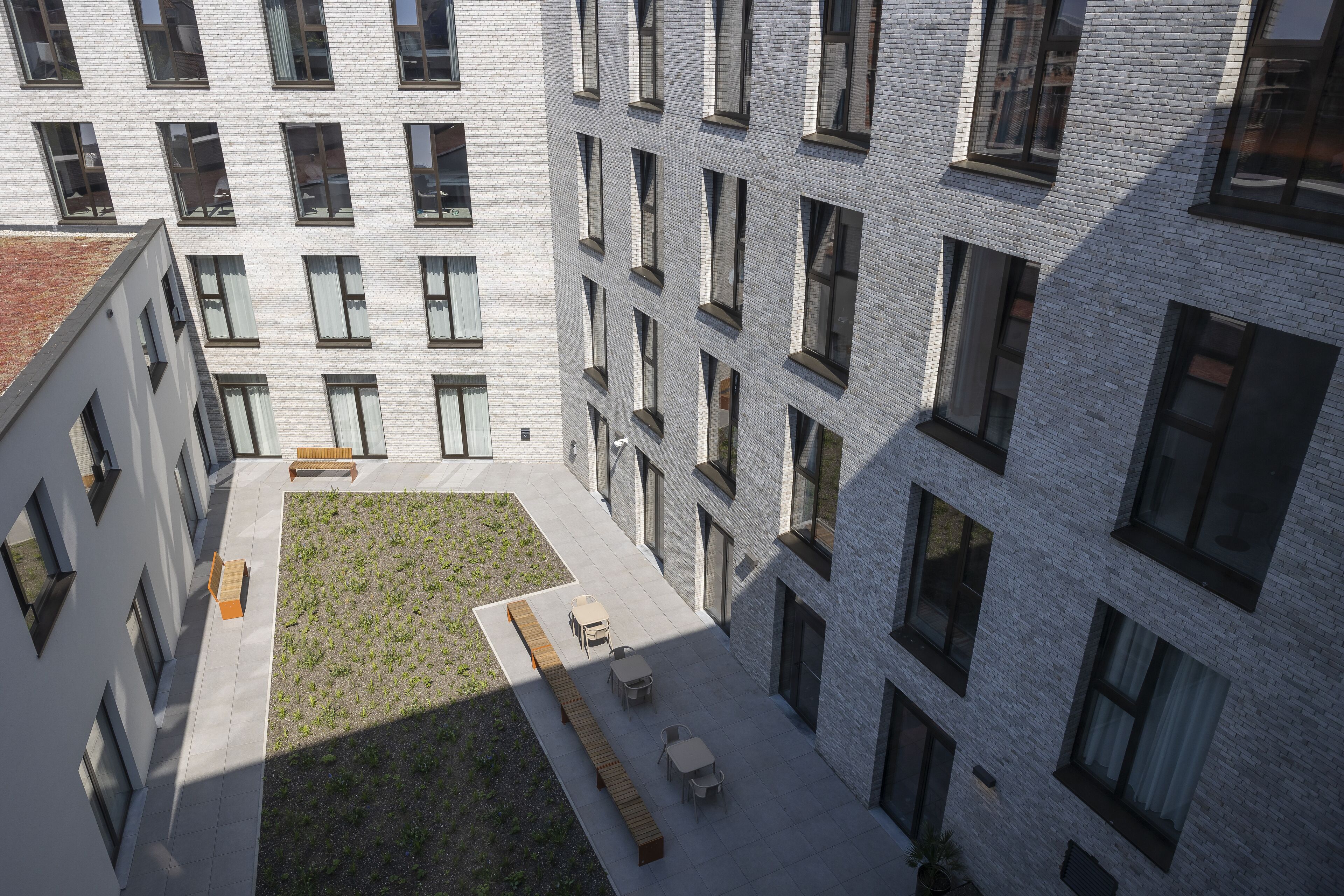 A courtyard with a long bench, tables, and chairs.