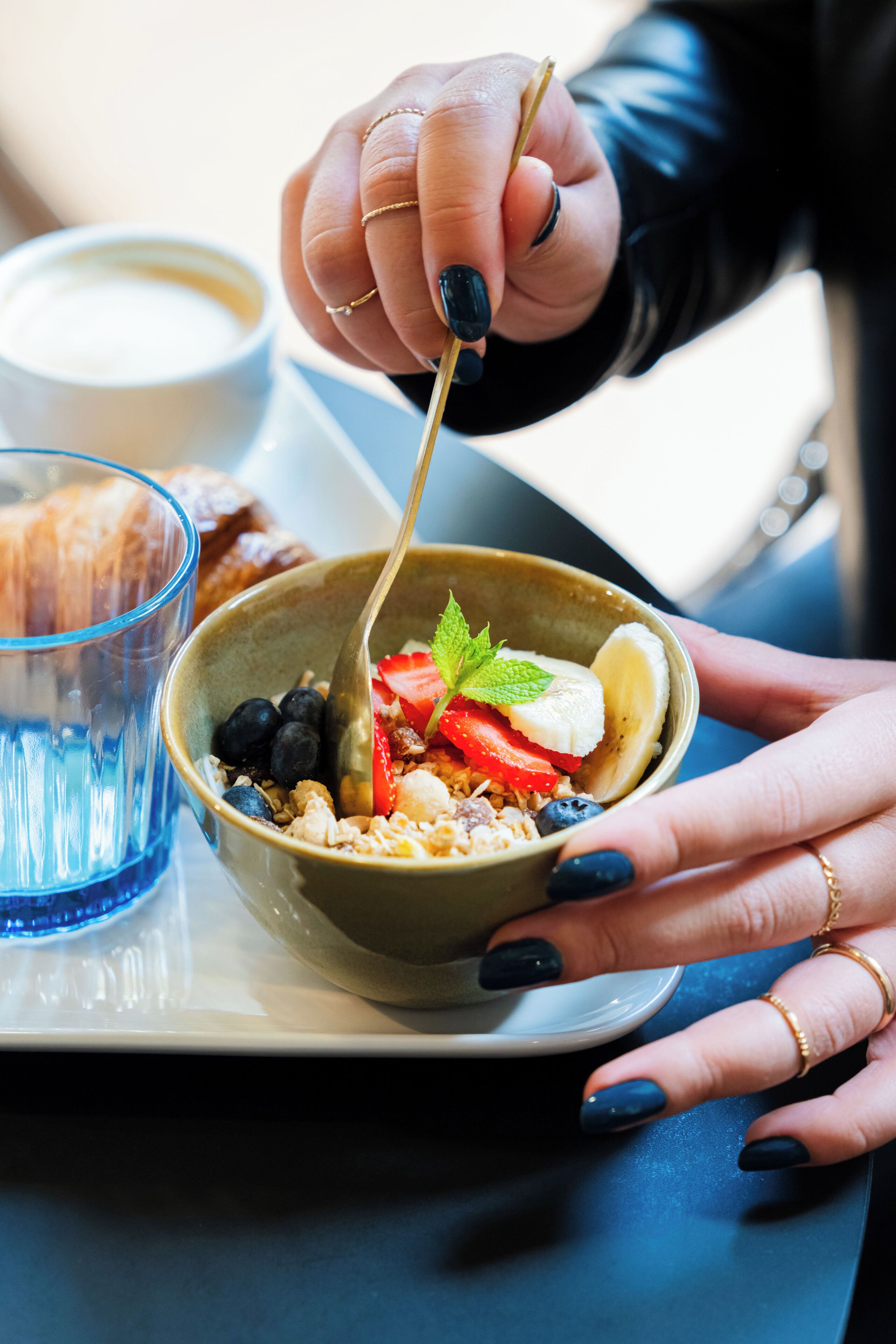 A bowl of cereal with fruits and a spoon.