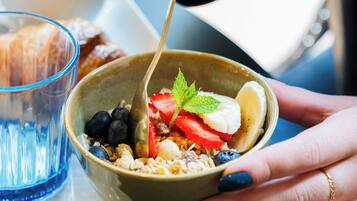 A bowl of cereal with fruits and a spoon.