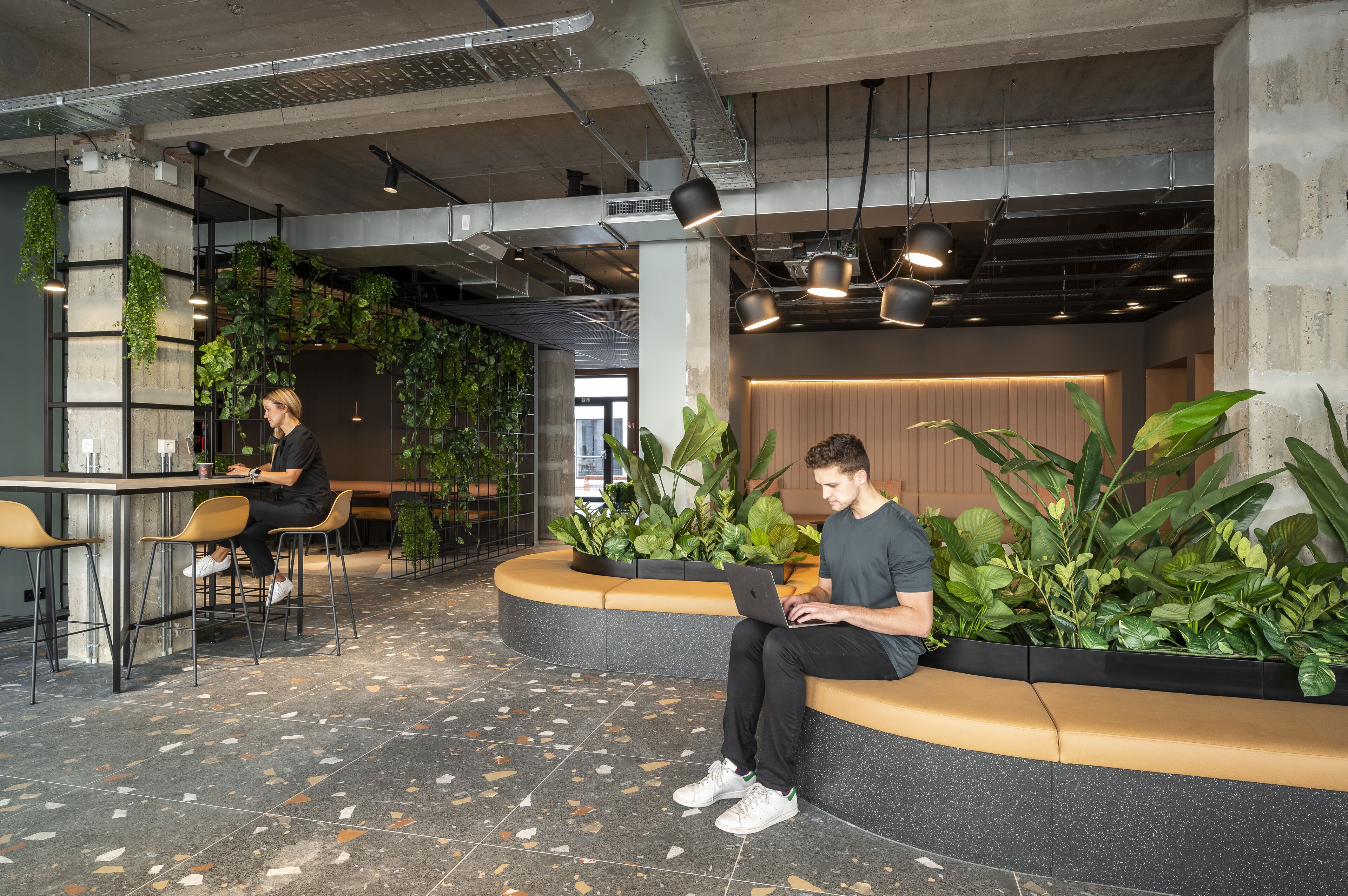 A modern indoor space with seating areas, a bar, and indoor plants.