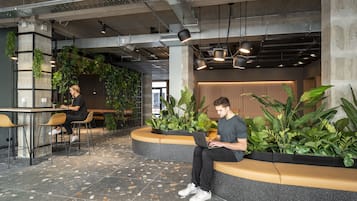 A modern indoor space with seating areas, a bar, and indoor plants.