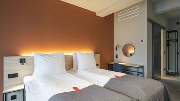 A hotel room with a large bed, bedside tables, a desk, and a shower area.