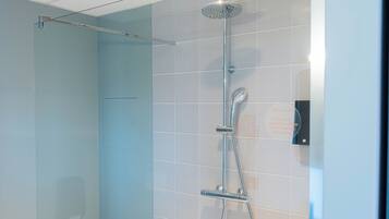 Une douche moderne dotée d’un pommeau de douche à pluie et d’un pommeau de douche à main, d’une paroi en verre et d’un panneau de commande mural.