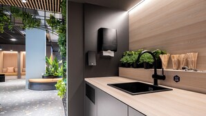 A modern kitchen with a black sink, wooden countertop, and a wall-mounted soap dispenser. - Citybox Antwerp City Center (Antwerp)