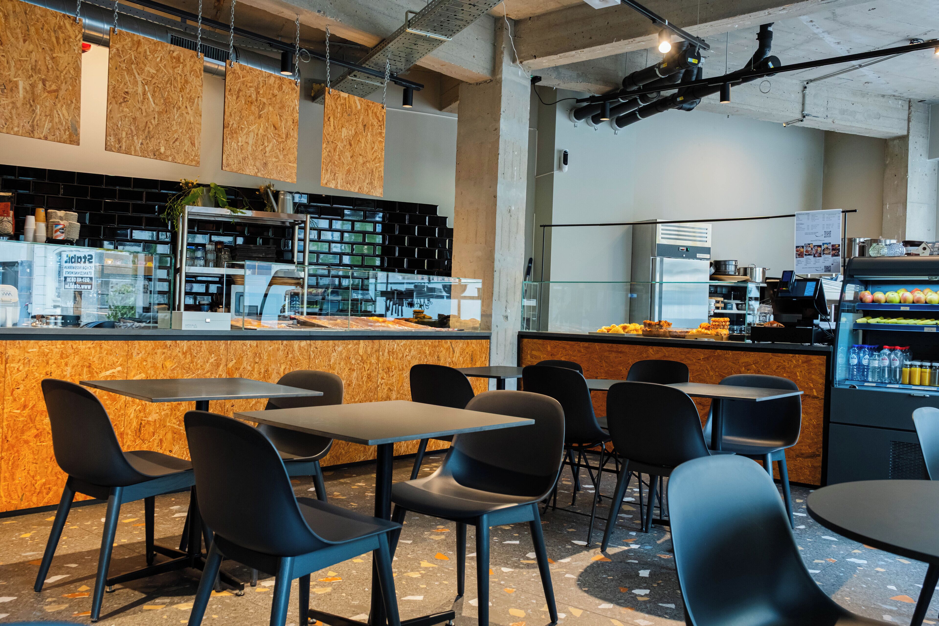 A modern cafe interior with a counter, seating area, and a beverage dispenser.