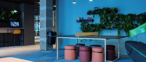 Un espace de bureau moderne avec un mur d’accent bleu, un coin bar et un aménagement avec des tabourets et des poufs.