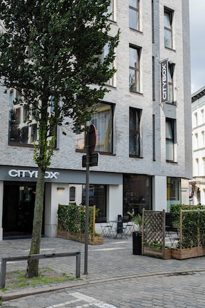 A modern building with a 'CITYBOX' sign, outdoor seating, and a tree in front.