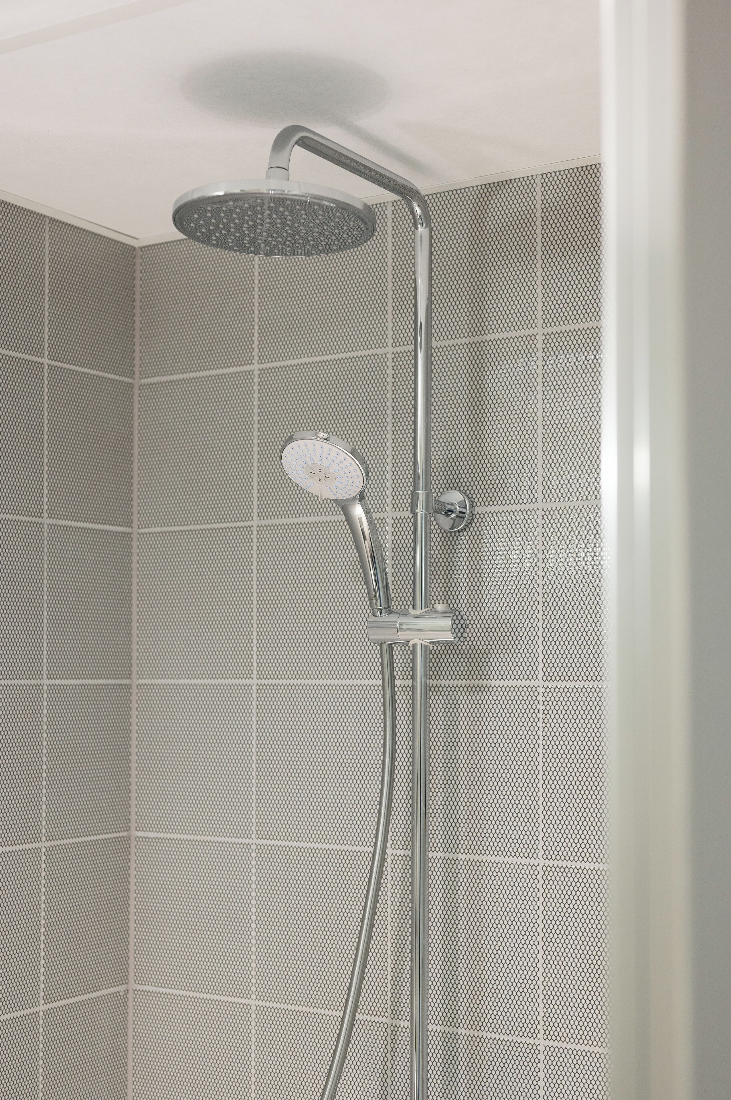 A modern shower with a handheld showerhead and a wall-mounted control.