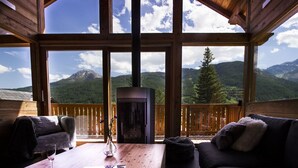 Una cabaña de madera con un ventanal grande que da a un paisaje montañoso.
