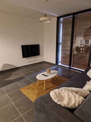 A modern living room with a flat-screen TV, a round coffee table, and a sofa.