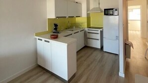 A modern kitchen with white cabinets, a yellow countertop, and a microwave.