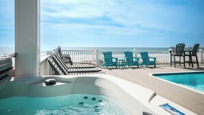 Una terrazza con idromassaggio, piscina e sedie con vista sull'oceano.