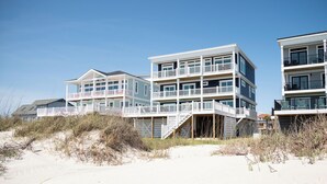 Una proprietà fronte spiaggia con edifici a più piani, balconi e un molo in legno.