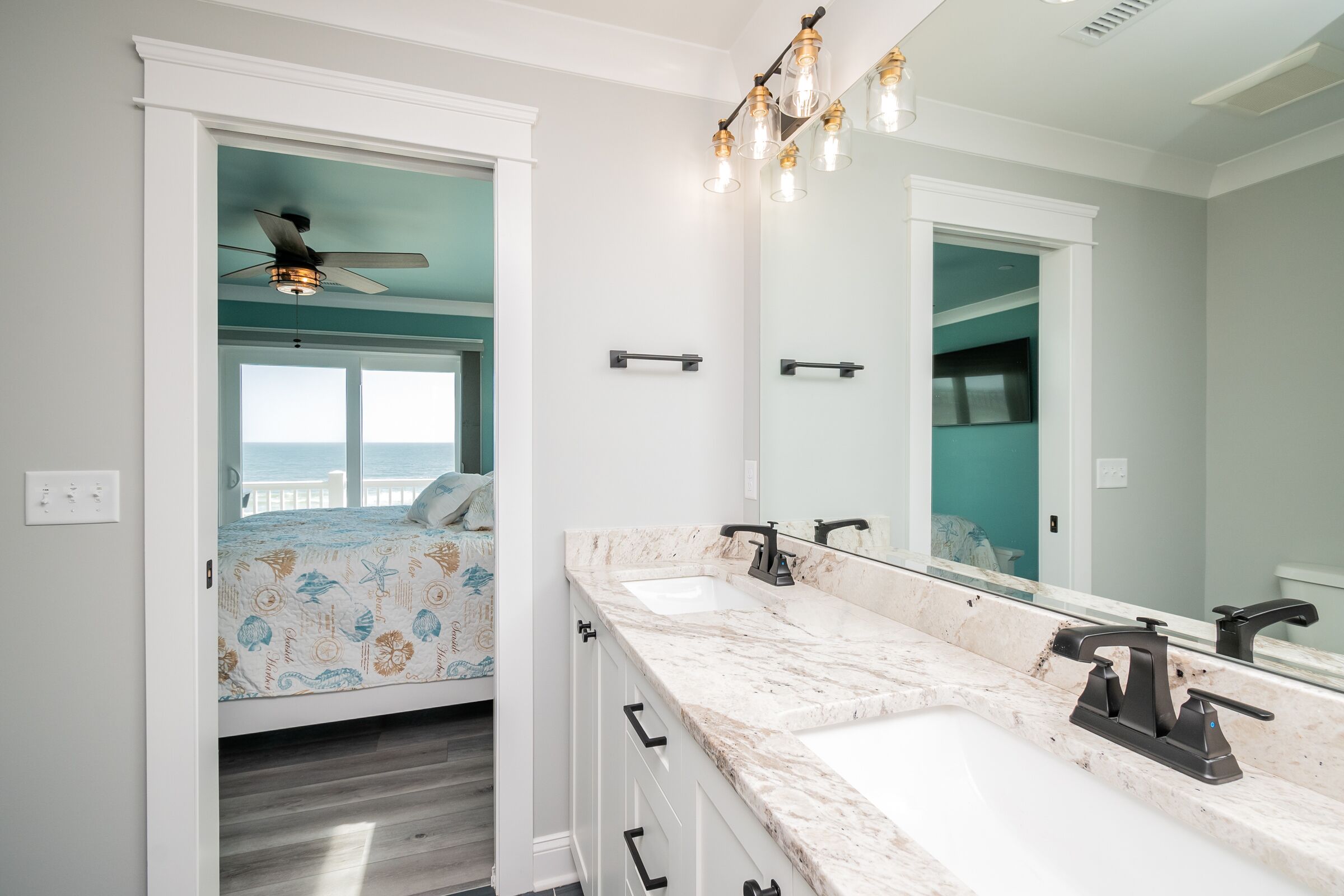 A bathroom with a double sink, a ceiling fan, and a large mirror.